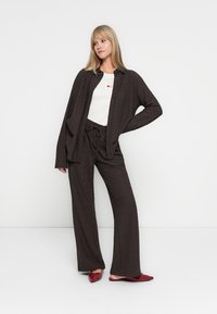 Set di abbigliamento lounge marrone a trama con camicia a bottoni e pantaloni a gamba larga. La parte superiore presenta una maglietta di cotone bianco con accenti a forma di cuore rossi.