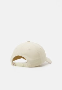 Beige színű baseball sapka ívelt Sipkával, textilanyagból készült, hátul állítható pánttal, és hímzett "EST 1922" felirattal a hátsó részén.