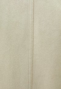 Beige suede fabric with a fine texture and visible stitching detail. The surface is smooth, featuring a seamless vertical seam.