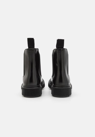 Black Chelsea boots with a shiny, patent finish. Features elastic side panels and a textured rubber sole for grip.