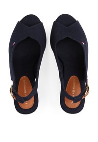 Sandales en toile navy avec un bout ouvert, une bride de cheville et des accents en cuir marron au niveau de la boucle. Semelles intérieures texturées visibles.