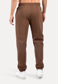 Brune sweatpants med elastisk talje og sidelommer, med en glat tekstur og taperet ben-design. Klassisk atletisk stil.