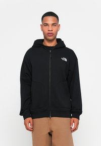 Black zip-up hoodie made of smooth fabric, featuring a front zipper, two side pockets, and a logo on the upper left chest area.