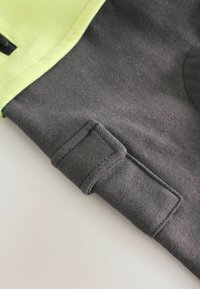 Szary i limonkowo-zielony sweatshirt z teksturowanym materiałem, detalem przeszytych mankietów oraz gładkim, jednolitym wzorem.