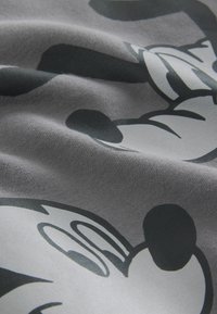 Harmaa kangas, jossa on toistuva musta-valkoinen Mikki Hiiri -kuvio, jossa on sileä pinta ja lievää ryppyisyyttä, tuoden esiin designin yksityiskohdat selkeästi.