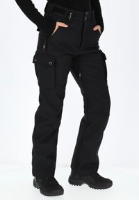 Pantaloni cargo neri da esterno con una vestibilità snella, dotati di molteplici tasche con zip e cuciture rinforzate. Tessuto testurizzato e hardware resistente.