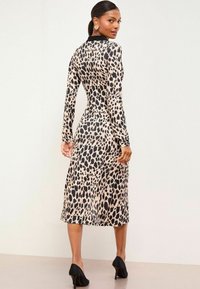 Šaty s dlhým rukávom s leopardím vzorom, priliehavého strihu, po lýtka, vyrobené z hladkej látky, s čiernym golierom a elegantnými lodičkami.