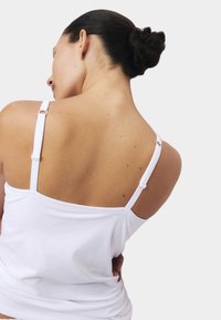 Witte slim-fit top met verstelbare bandjes. Zachte stof, minimalistisch ontwerp, met een gladde rug en subtiele naaddetails.