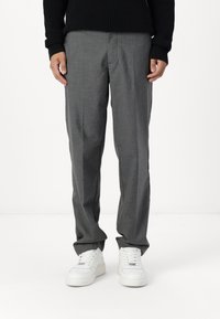 Pantaloni grigi su misura con una texture liscia, caratterizzati da un design a gamba dritta. Abbinati a scarpe da ginnastica bianche per un look casual.