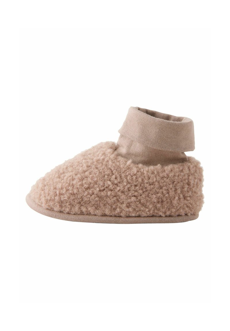Zapatillas de lana beige acogedoras con una parte superior suave y texturizada y un puño de tela lisa en contraste en el tobillo, con punta redonda y suela plana.