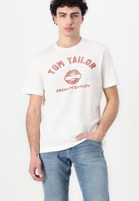 Hvit bomulls T-skjorte med grafikk av røde lepper og teksten "TOM TAILOR PREMIUM QUALITY." Kortermet med rund hals-design.