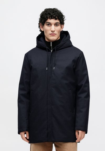 Tumesinist kapuutsiga jope siledast kangast, millel on pikad varrukad, esimesed taskud ja tõmblukuga sulgur. Lihtne disain, sirge lõige.