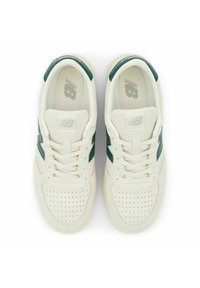 Vita sneakers med gröna detaljer, perforerad tå och texturerat läder på ovansidan. Har skosnören och en logga på tungan. Gummisula.