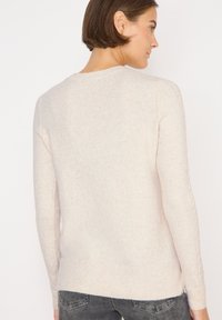 Hellrosa Pullover mit langen Ärmeln, einem runden Ausschnitt und einem strukturierten Strickdesign. Mit gerippten Bündchen und Saum. Minimalistischer Stil.