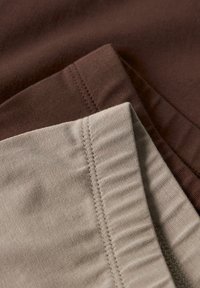 Twee stofmonsters: één in donkerbruin en één in lichtbeige. Beide hebben een gladde textuur met zichtbare stiksels langs de randen.