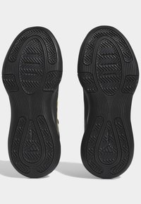 Sole di scarpe sportive nere con motivi testurizzati, caratterizzate da un design a spina di pesce e con branding, adatte per il basket o attività sportive.