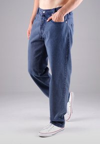 Blaue Denim-Jeans mit einer lockeren Passform, die ein klassisches Fünf-Taschen-Design, einen Metallknopfverschluss und kontrastierende Nähte aufweisen.