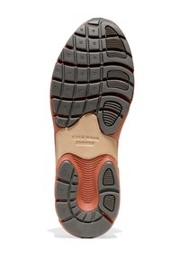 Suela de zapato con una banda de rodadura de goma texturizada negra y una superposición sintética marrón claro. Cuenta con surcos y puntos para tracción y soporte.