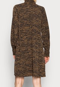 Brun klänning med ett svart tigerstrimmönster, hög halsringning, långa ärmar och avslappnad passform med rynkade manschetter och en mittbak-söm.