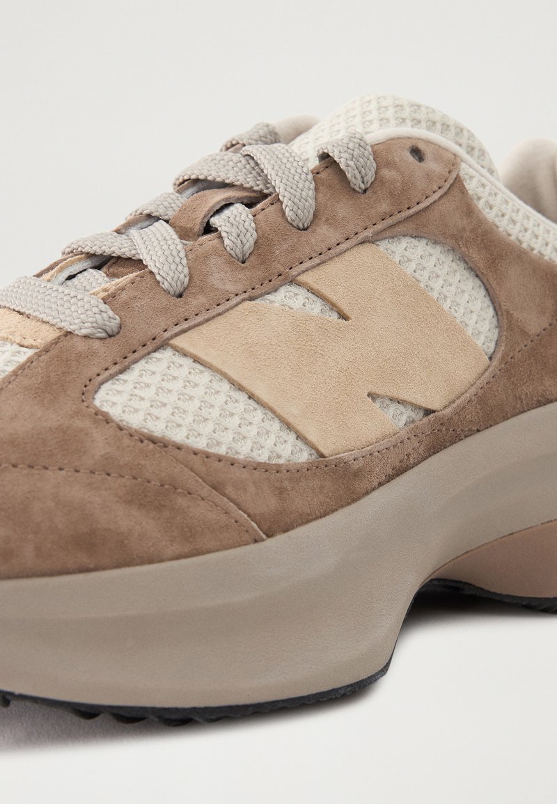 Sneaker in suede e rete marrone con collo imbottito, dettagli beige e una suola in gomma grigia spessa con un motivo testurizzato.
