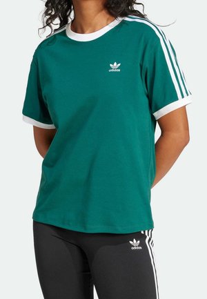 Zielona bawełniana koszulka z białym prążkowanym kołnierzem i mankietami, z trzema białymi paskami na ramionach i małym białym logo Adidas na piersi.