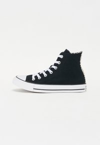 Sorte høyhælte sneakers laget av lerret, med hvite snører, en gummitåhette og en teksturert aksent ved hælen. Svarte og hvite stripete såler.