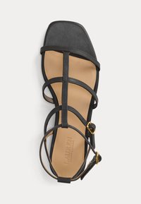 Sandália preta com tiras, ponta quadrada, parte superior em couro e palmilha bege com marca; inclui uma tira no tornozelo com detalhes em dourado.