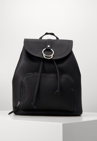 Czarny skórzany plecak z zaokrągloną klapą, srebrnymi akcentami, zapięciem na sznurek oraz przednią kieszenią na zamek. Teksturowana powierzchnia, minimalistyczny design.