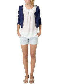 Námořnický kardigan zapnutý vpředu přes bílou plisovanou blůzu, doplněný světlomodrými šortkami a béžovými sandály. Jednoduchý a ležérní outfit.