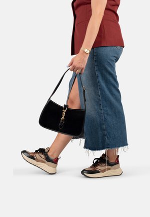 Sac à main noir avec quincaillerie dorée, associé à une longue jupe en denim avec un ourlet brut, et des baskets à imprimé animal avec des semelles épaisses.