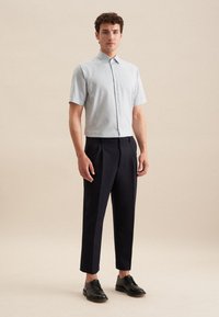 Korte mouwen, lichtblauw en wit gestreept shirt met een button-down kraag, gecombineerd met op maat gemaakte zwarte broeken en zwarte schoenen.