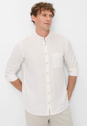 Camicia button-up bianca in lino con colletto alla francese, taschino singolo sul petto e maniche arrotolate. I bottoni sono di colore chiaro e ben distanziati.