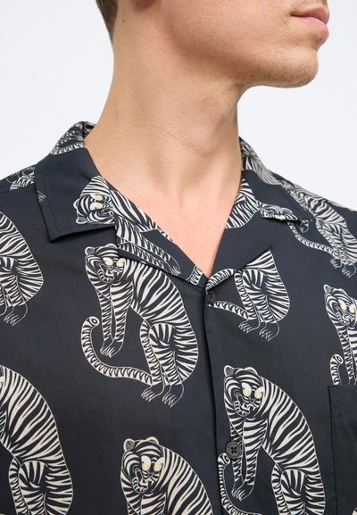 Kurzarmhemd aus schwarzem Stoff mit einem weißen Tiger-Muster. Glatte Textur mit einem Button-Down-Kragen und einer Taschenverarbeitung auf der Brust.