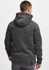 Gray, flecked hoodie with a large hood, ribbed cuffs, and hem. Features a pocket on the side and soft, textured fabric.