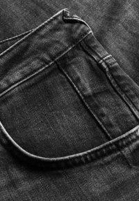 Svart denimtyg med en bakficka med rundad topp och sydda sömmar, som visar en texturerad finish och subtila tonala variationer.