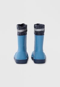 Bottes de pluie en caoutchouc bleu avec une surface texturée, un design haut et des poignets en tissu bleu marine ornés d'une bande réfléchissante en haut.