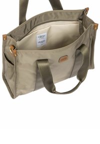 Sac fourre-tout rectangulaire beige avec poignées en tissu duales, poches latérales, ouverture en haut et doublure intérieure beige avec une petite étiquette à l'intérieur.