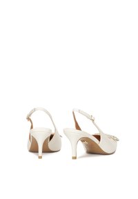 Tacchi slingback bianchi con punta affusolata e un accento decorativo di strass nella parte anteriore. Texture liscia, tacco affusolato con punta dorata.