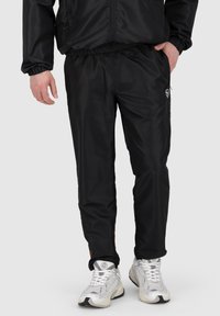 Zwarte synthetische jogpants voor heren met een elastische tailleband, een gladde textuur en een logodetail op de linker bovenbeen.