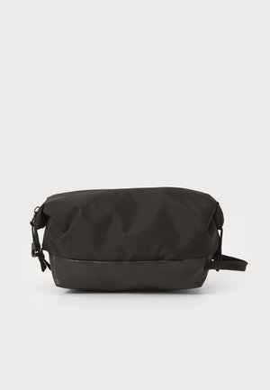 Necessaire preta com fecho, feita de tecido texturizado com um fundo liso. Apresenta uma alça de transporte e uma forma retangular compacta.