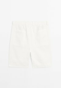 Shorts en coton blanc avec une taille élastique, deux poches arrière et une coupe droite. Texture lisse sans motifs visibles.
