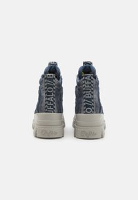 Baskets en textile bleu avec des accents en cuir, semelle épaisse beige et onglet de talon de marque proéminent en couleur contrastée.