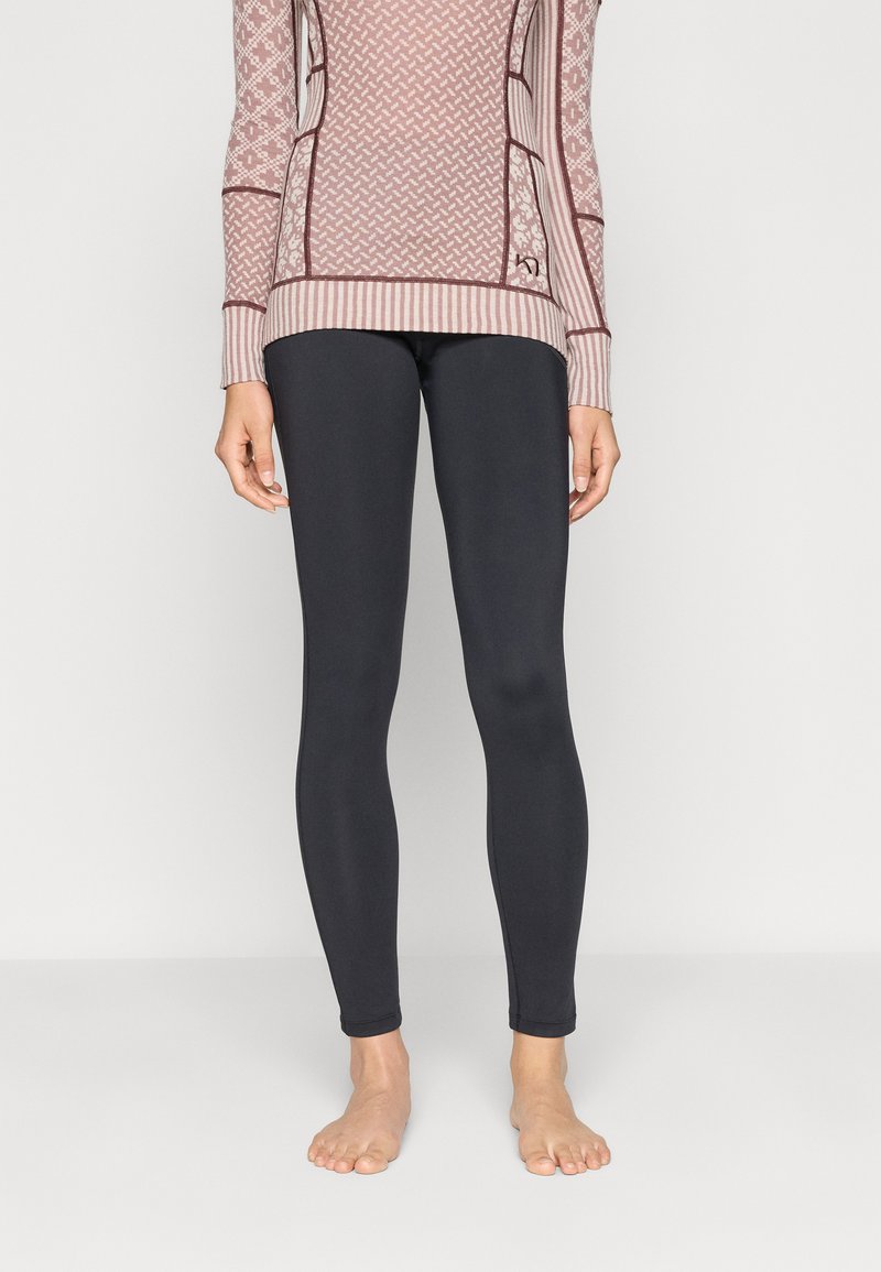 Leggings noirs à texture lisse, design ajusté et sans coutures visibles. Associés à un haut à manches longues à motifs de couleur rose clair et blanc.