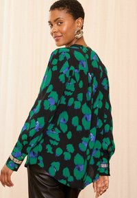 Fekete blúz zöld és kék absztrakt mintával, hosszú ujjú, gombos mandzsettával és ívelt aljjal. Könnyű anyagból készült.