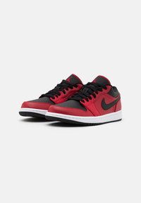 Röda och svarta låga sneakers med läderöverkänsla, perforerad tåbox, vit mellansula och svart gummiyttersula. Har en svart Nike swoosh.