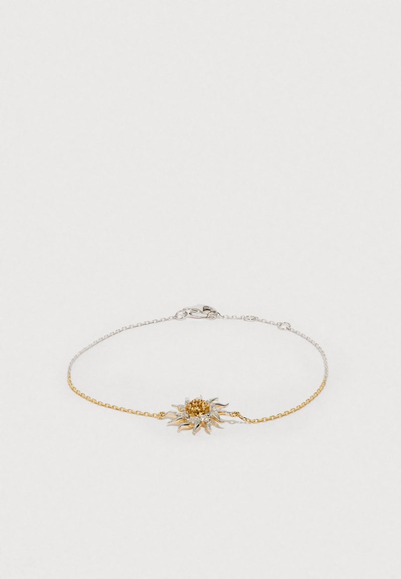 Náramek ze zlata a stříbra se slunečním motivem uprostřed, obsahující texturovaný, kulatý zlatý kámen a jemné články řetízku.