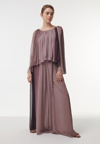 Vestido largo y fluido en suave color malva, con tela en capas, cuerpo plisado y un adorno de cuentas decorativas en el lateral. Mangas transparentes.