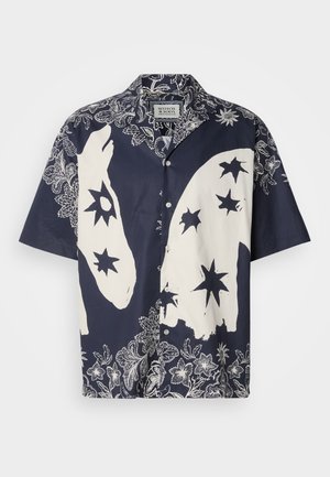 Chemise à manches courtes en coton bleu marine et crème, avec de grands motifs d'étoiles blanches et de fleurs, dotée d'un col et d'une fermeture à boutons.