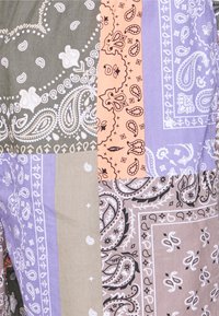 Tessuto multicolore caratterizzato da motivi paisley in grigio, lavanda, pesco e beige. Tessuto texturizzato con dettagli intricati.