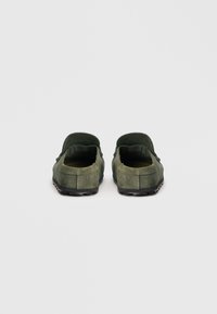 Grønne semskede slip-on sko med en flad sort gummisål. Har en afrundet tå og lavskårne sider, som viser et minimalistisk design.